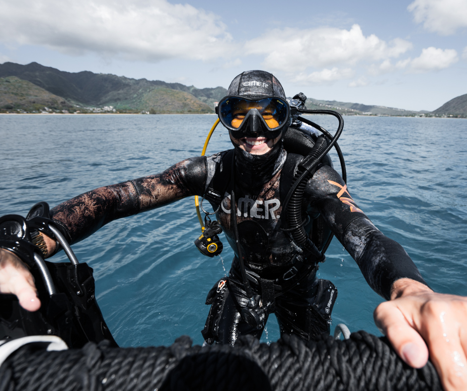 Smiling scuba diver climbing out of the water onto a boat